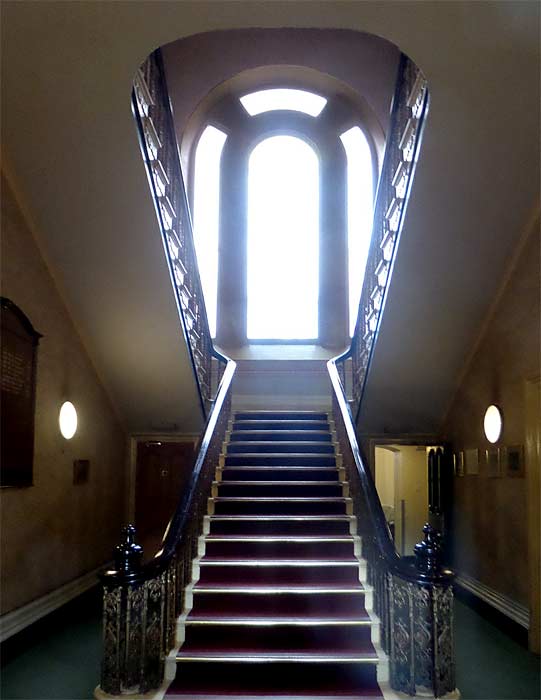 The sweeping staircase of the Oldham Lyceum and the stained glass window illuminating it.